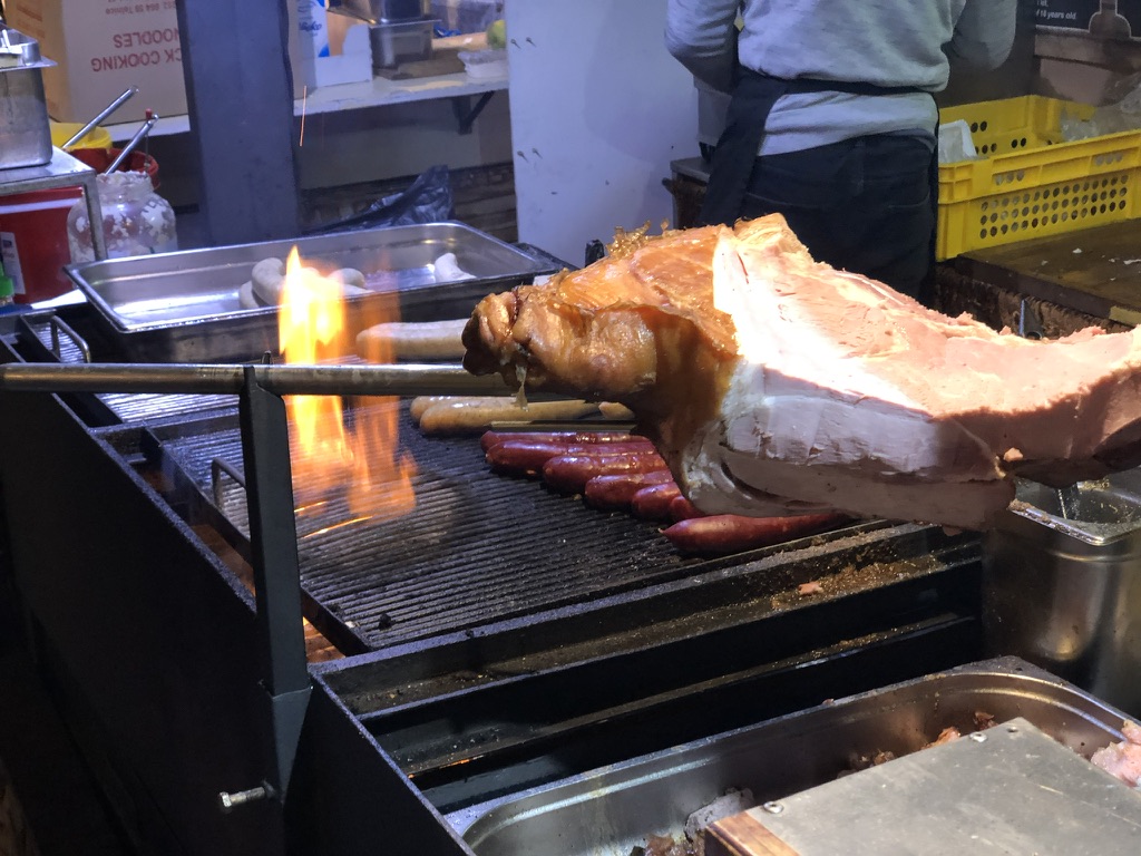 Roasting meat and sausages at a market food stall.