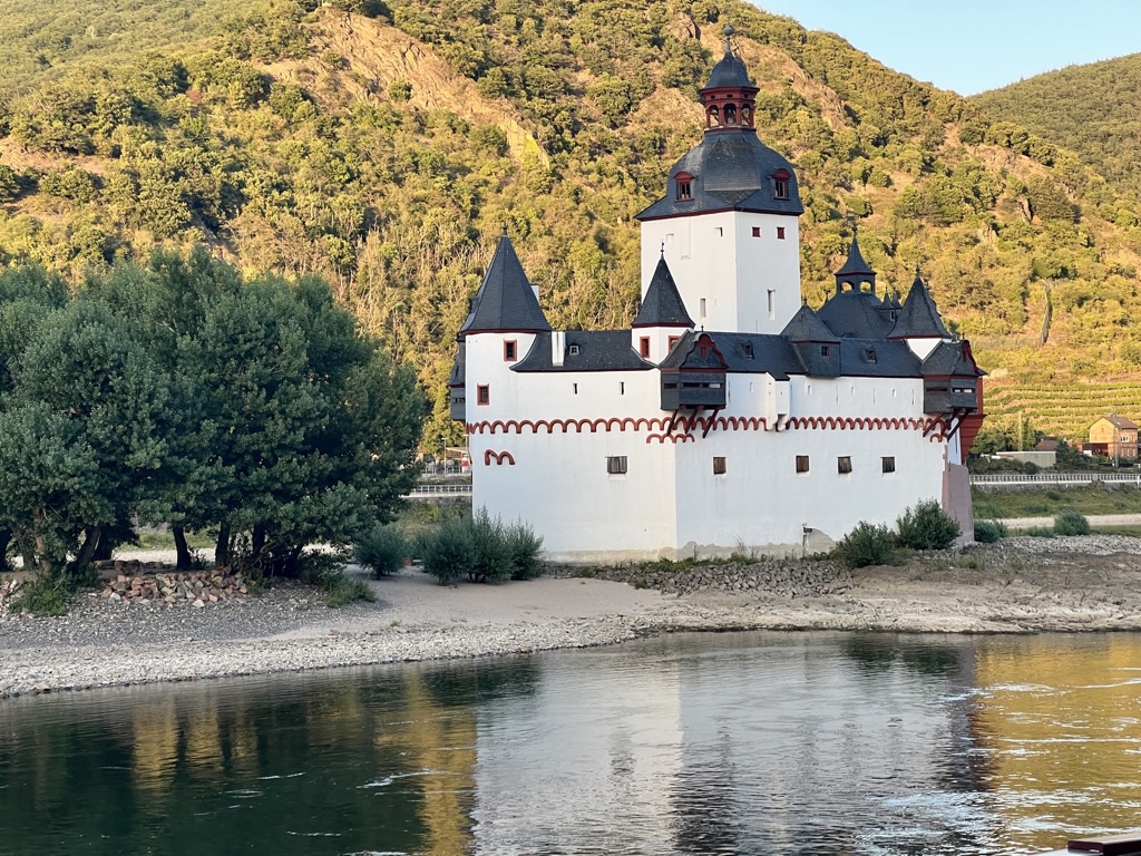 A white castle beside the river, with exposed shoreline below its walls.